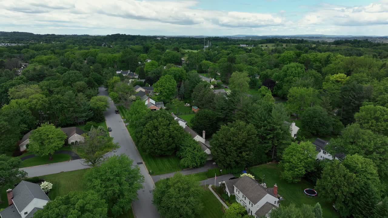 Luxury single family homes and houses between green trees in quiet suburbia. Aerial forward wide shot. Quiet and calm street