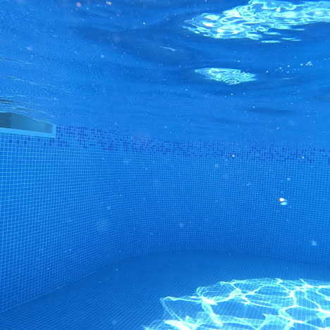 young boy jumps underwater into a pool. underwater shot with amazing bubbles inside the swimming pool. boy in blue water with beautiful bubbles splash.