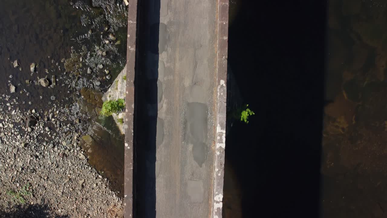 물, 돌 및 잎사귀 위에 있는  ⁇ 은 콘크리트 다리의 드론 영상