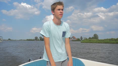 young man is sailing a electric sloop in the netherlands friesland in the summer in slowmotion