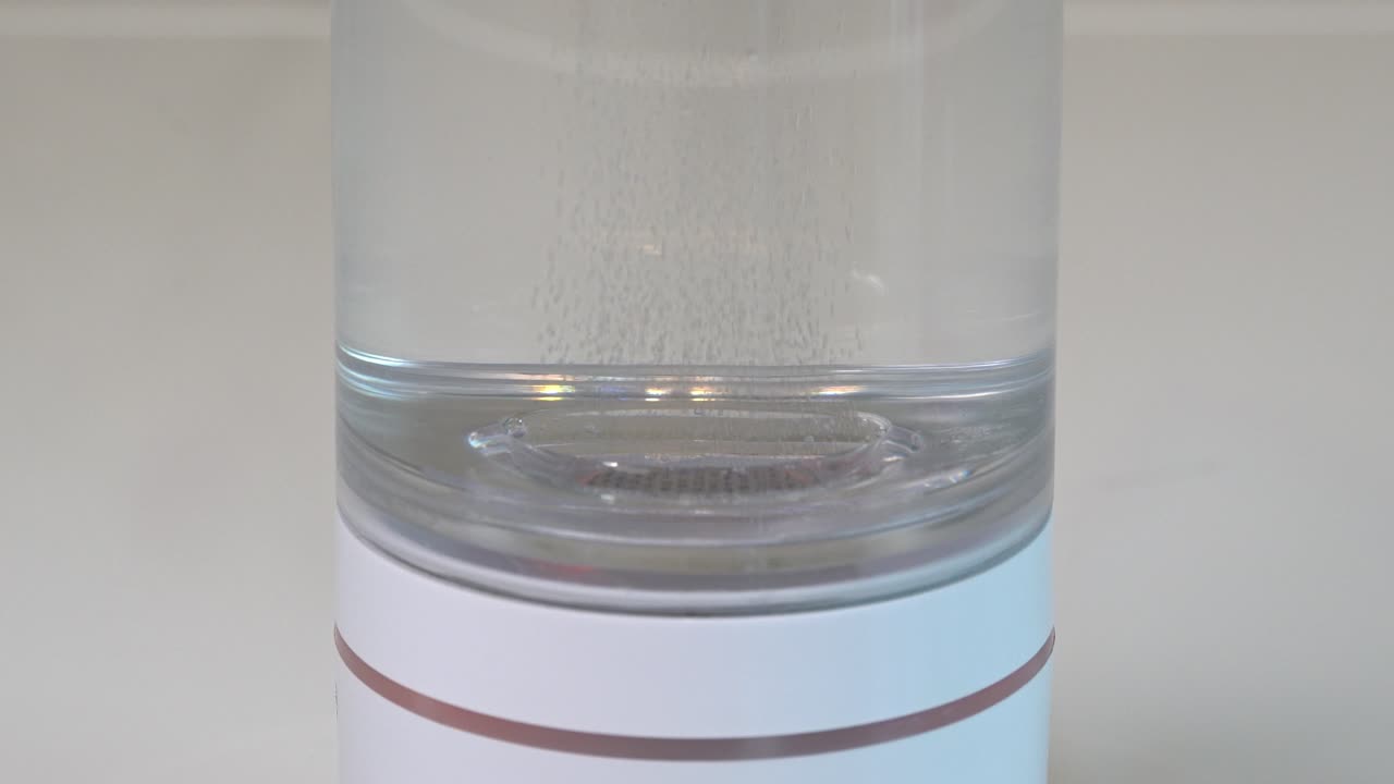 producción de gas hidrógeno a partir de la electrólisis dentro de una botella portátil de vidrio transparente - producto de salud alternativo