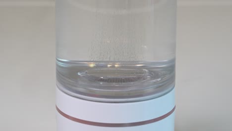 producción de gas hidrógeno a partir de la electrólisis dentro de una botella portátil de vidrio transparente - producto de salud alternativo