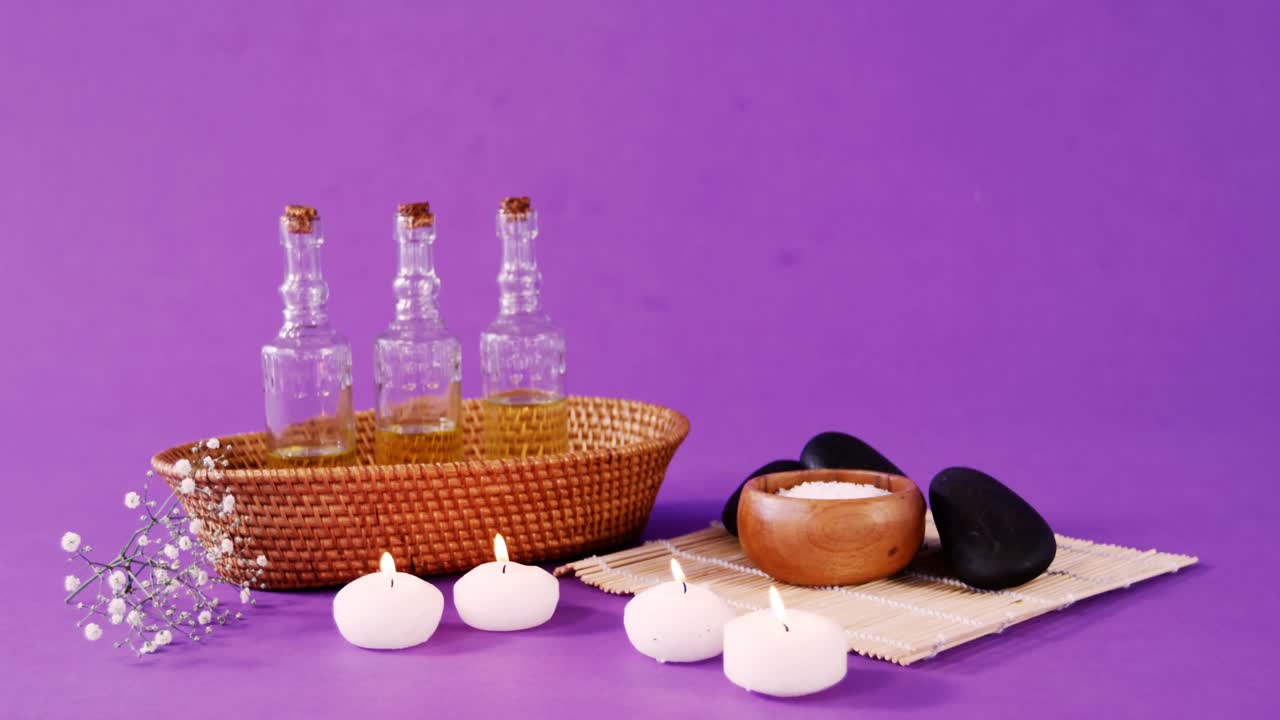 sal de mar en un cuenco de madera, guijarros, aceite, velas y flores