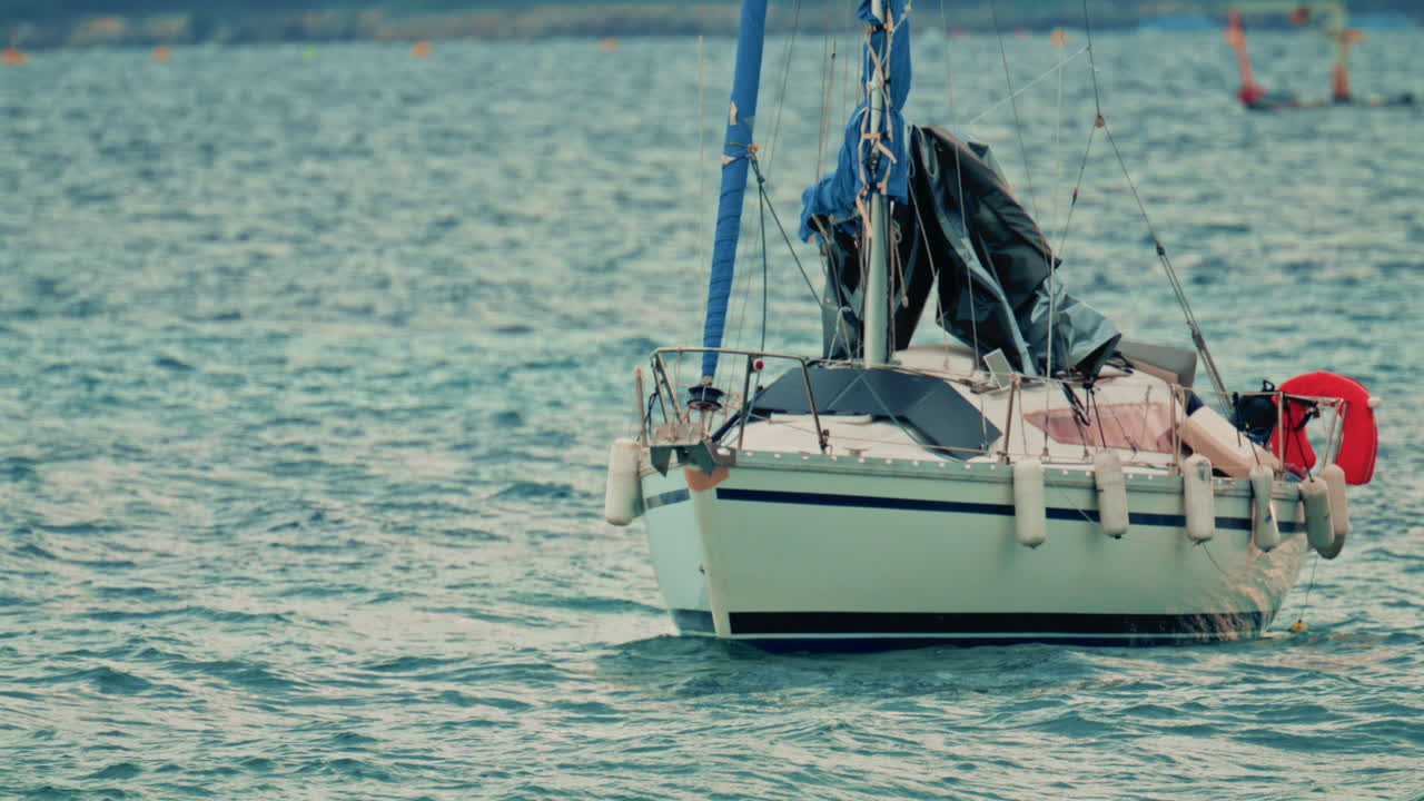 Vista di una piccola barca a vela cullata dalle onde con un marinaio solitario a bordo