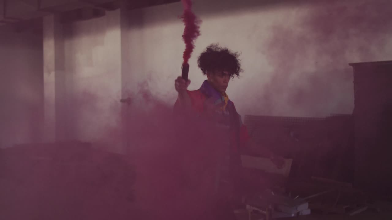 hombre de raza mixta sosteniendo una bengala púrpura caminando a través de un edificio vacío