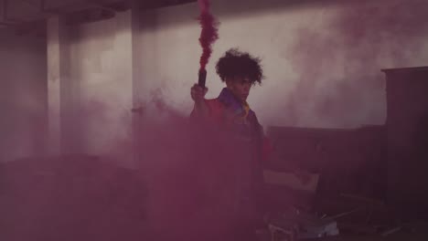 mixed race man holding purple flare walking through an empty building