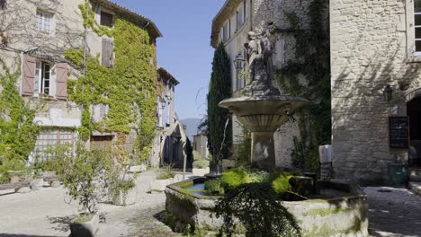 Kleiner-Dorfplatz-In-Einer-Historischen-Steinstadt-In-Frankreich-Bei-Gutem-Wetter-Mit-Schöner-Atmosphäre-Und-Pflanzen-An-Den-Alten-Häusern