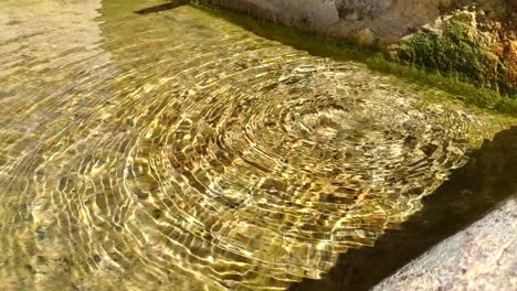 close up of an stone fountain from a small town full of crystal clear water