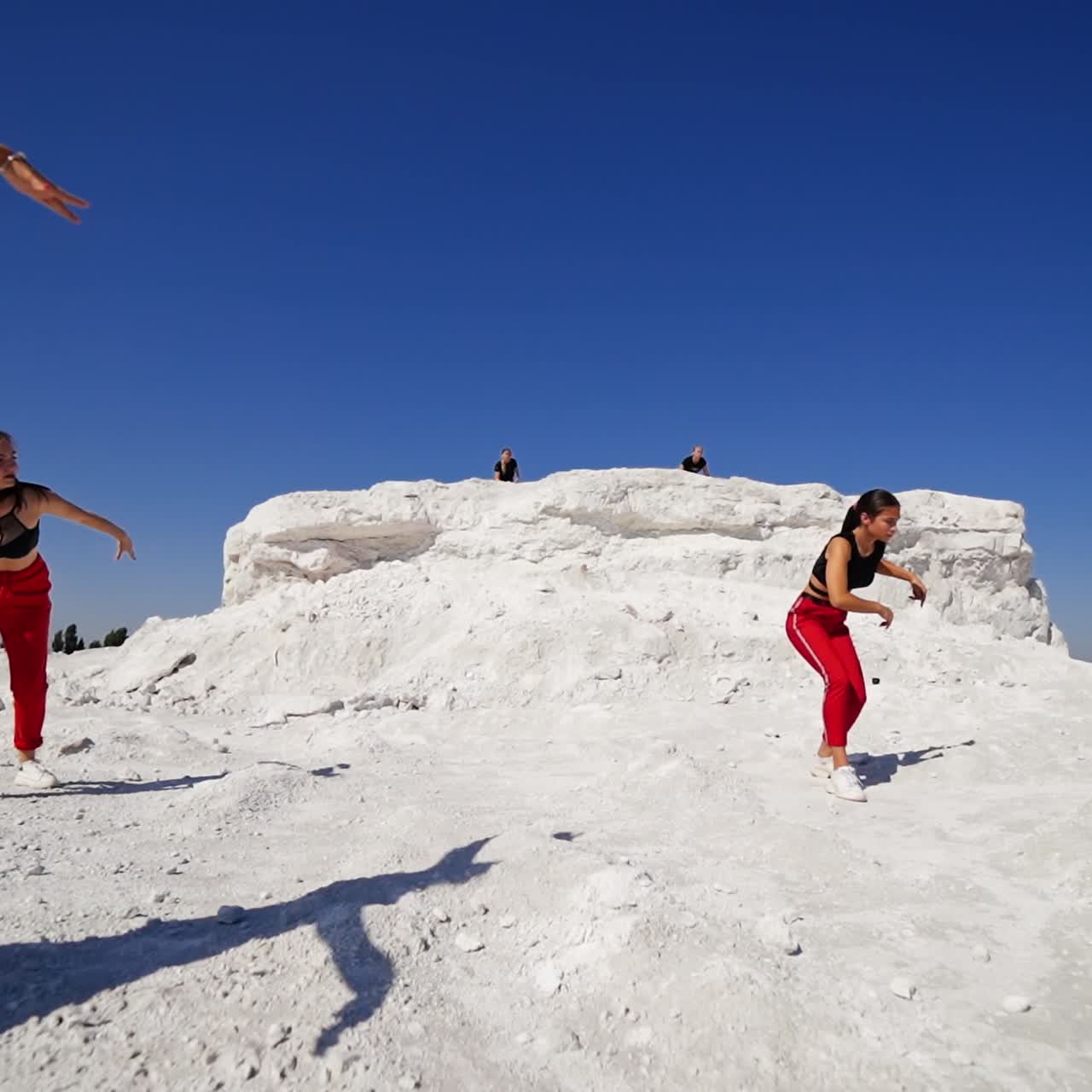 Young girls performing the active modern dance outdoors. Trendy dance style at the rocky white landscape on sunny day
