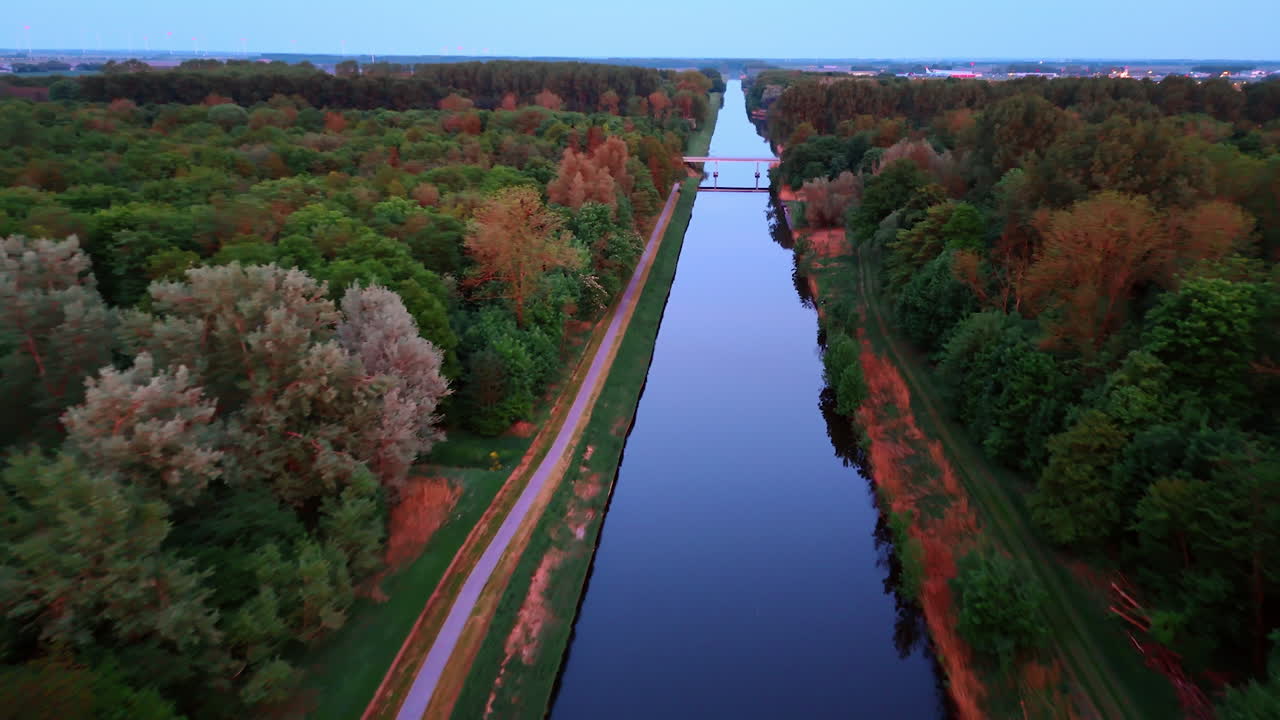 Sunset over the calm canal. A tranquil canal stretches through lush greenery during sunset, reflecting warm hues in the calm water