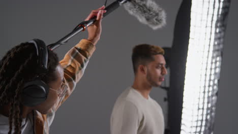 grabador de sonido de película masculino con auriculares sosteniendo el micrófono boom poste de grabación actor rodando película o video en estudio rodado en tiempo real
