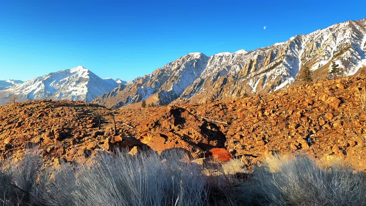 Full moon snowy Mount Tom Mt Thompson prominent towering peak West Bishop California aerial drone sunrise morning winter mountain Sierra Nevada Range Big pine rocky desert round valley slide right