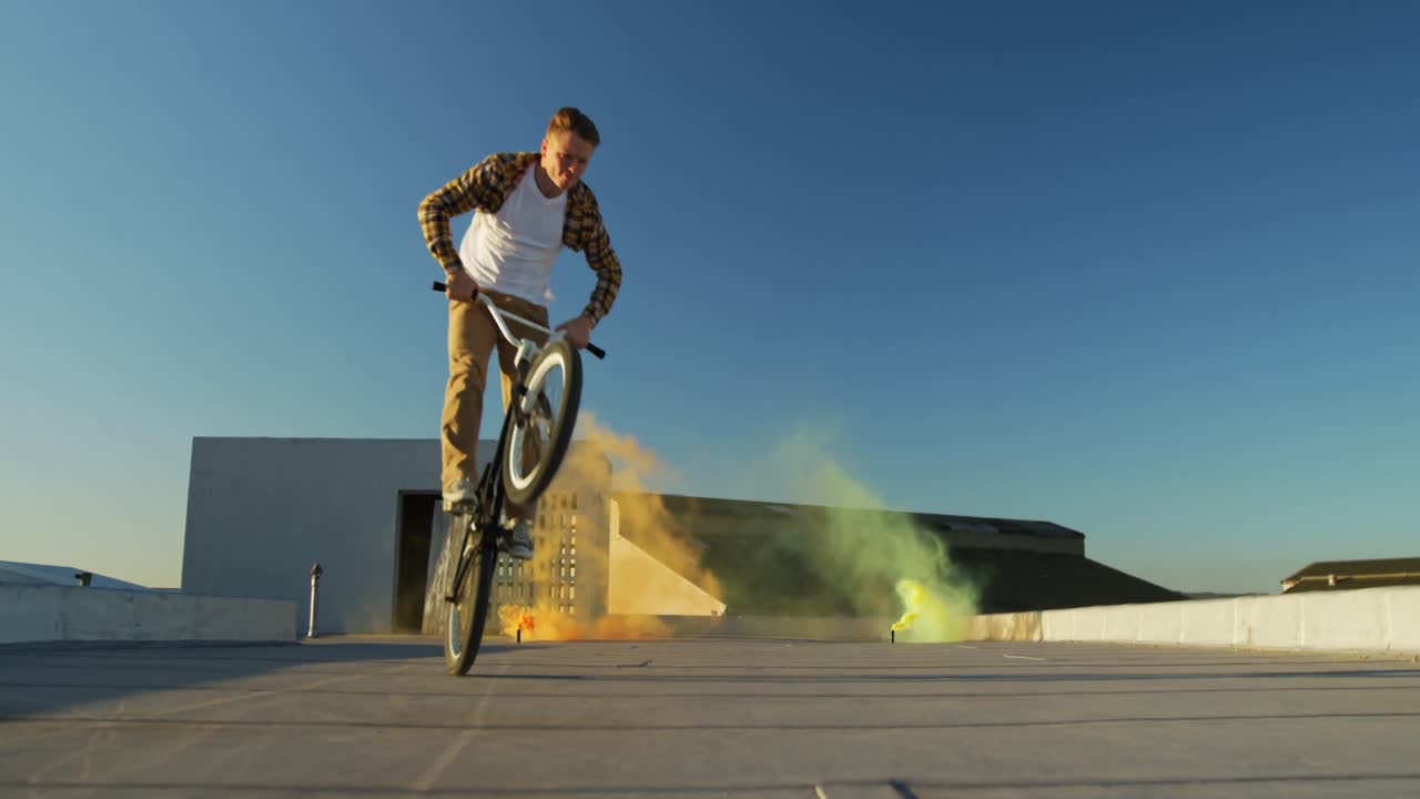 jinete de bmx en un techo saltando y usando granadas de humo