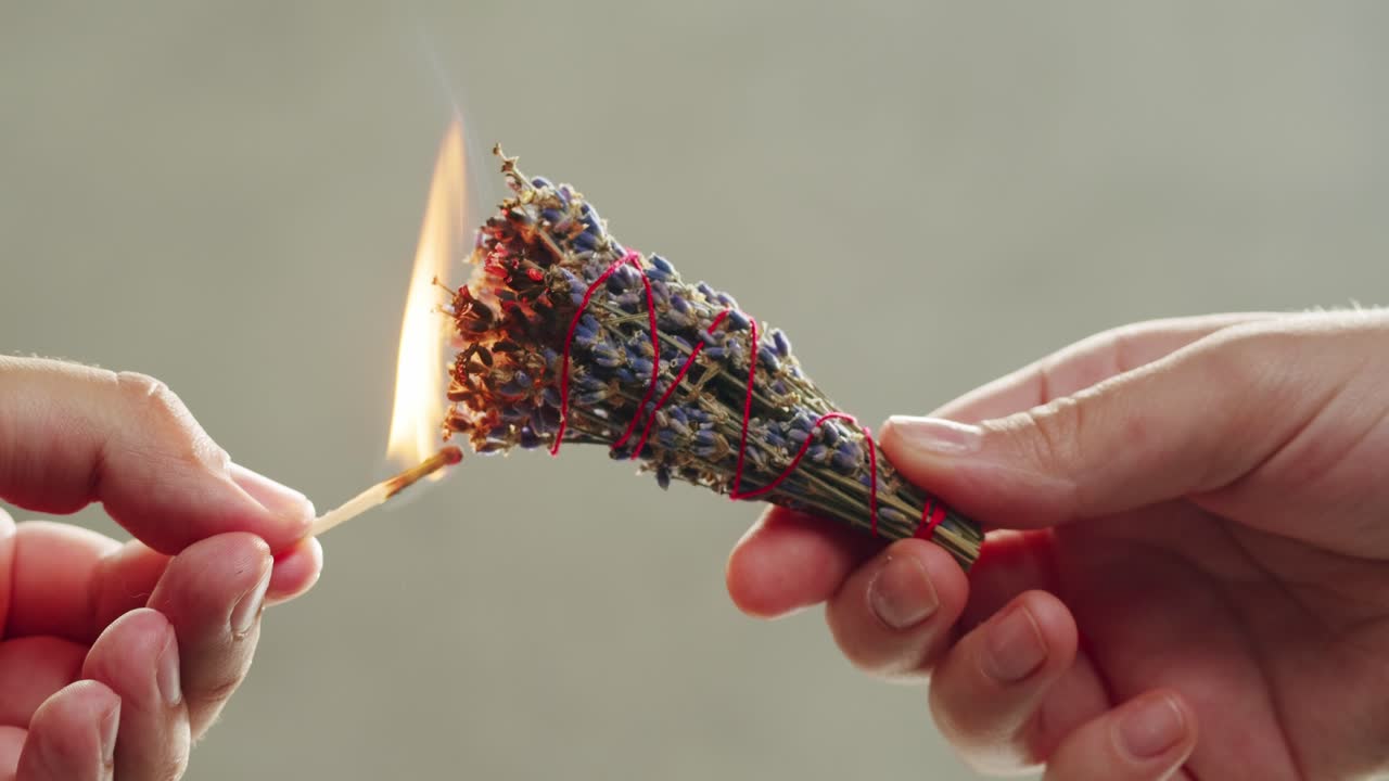 Person holding Palo Santo wood stick in hand, aromatic Palo Santo burning on black background, smoke spreading around, slow motion video clip, high quality 4k close up footage. High quality 4k footage
