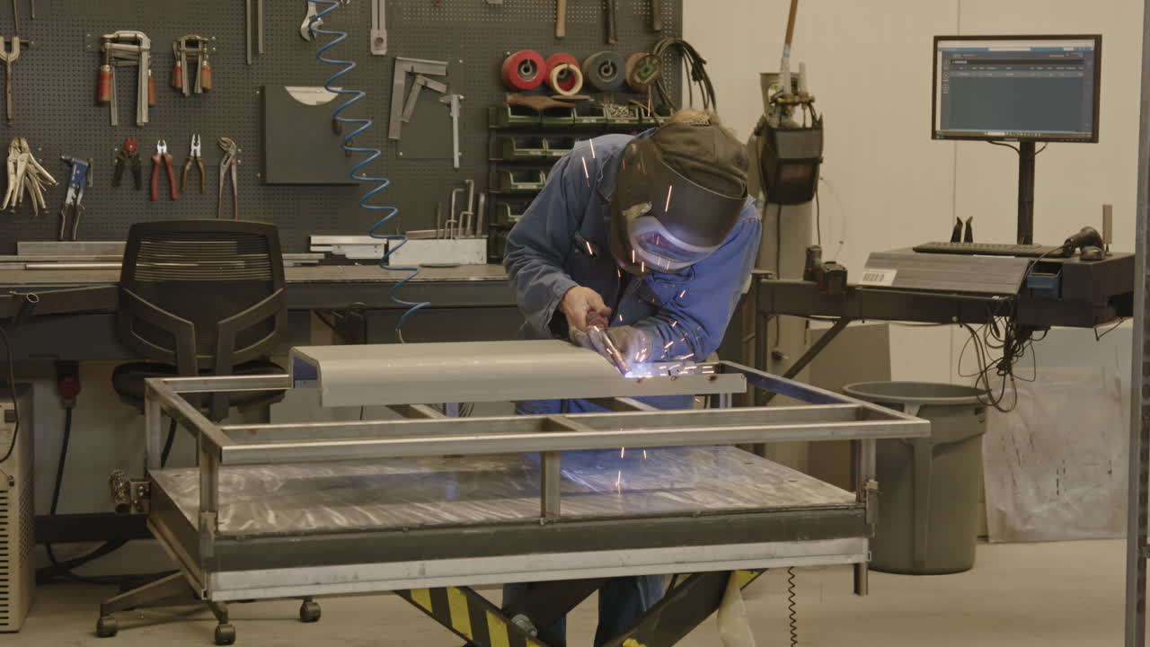 Wide shot of a man welding a frame in a workshop in slow motion