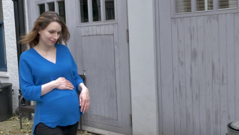 pregnant caucasian young woman crosses road in mews street