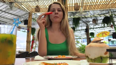 una mujer disfrutando de un plato de frutas en un café tropical.