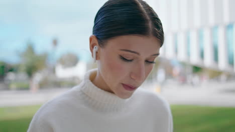 portrait woman talking outdoors using wireless earbuds. girl using headphones.