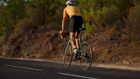 Cámara-Lenta-Captura-Al-Atleta-Pedaleando-A-Través-De-Una-Montaña-Serpenteante,-Contemplando-La-Belleza-De-La-Isla,-Encarnando-Los-Principios-De-Un-Estilo-De-Vida-Saludable