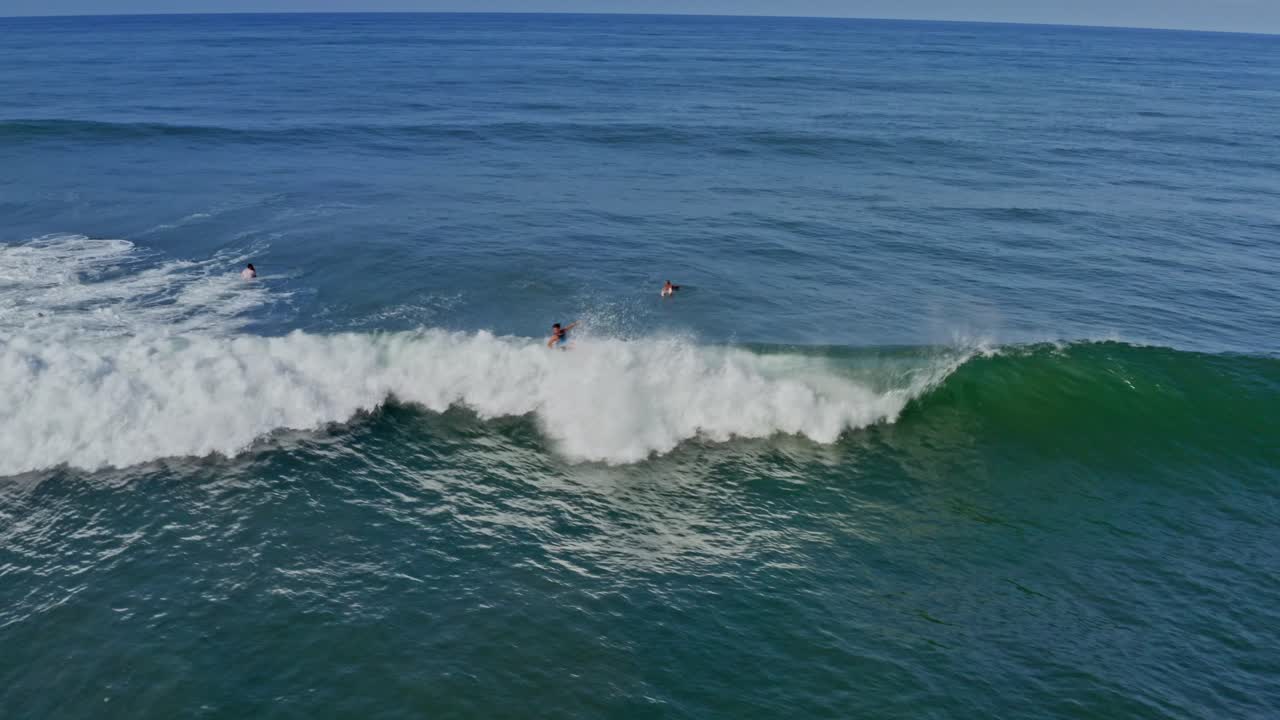 Aerea: surfista che cavalca e cade su una grande onda al largo della costa pacifica