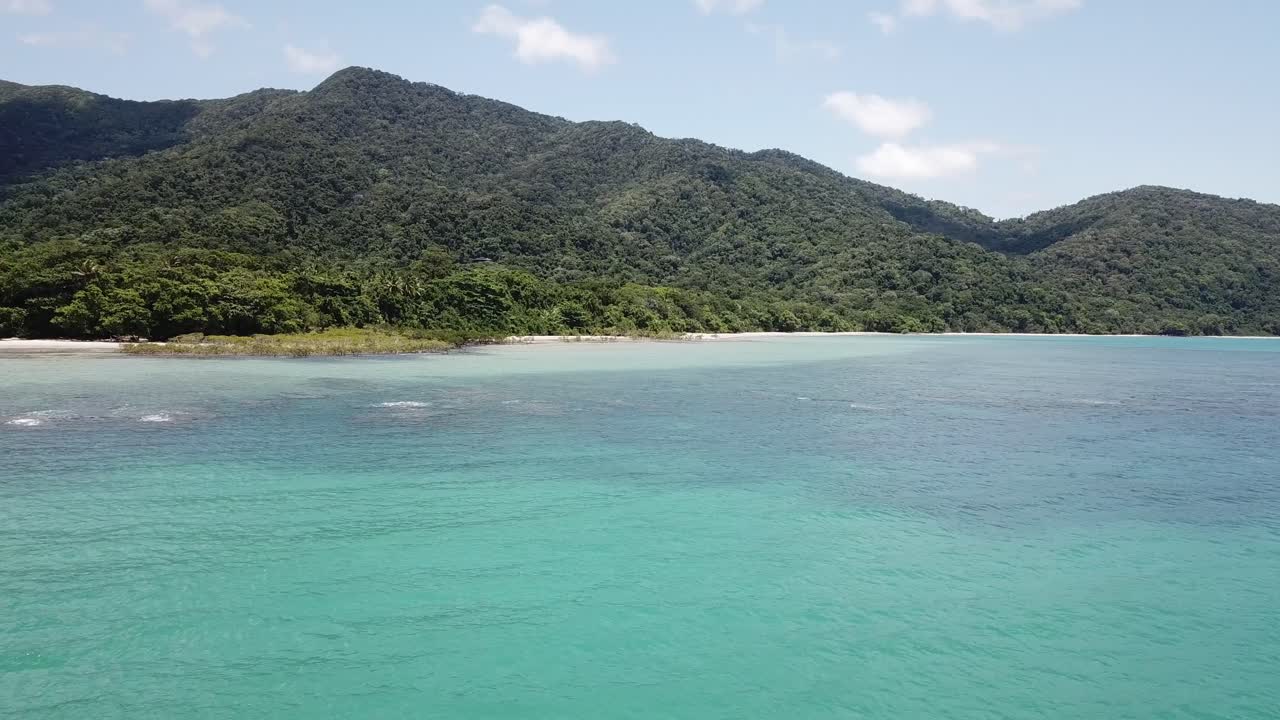 giro lento aéreo de drones bajos sobre los arrecifes del océano azul tropical y la selva tropical de daintree