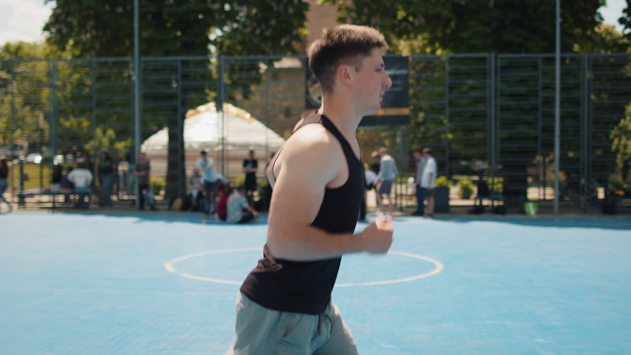Athletic caucasian sports man in sportswear jogging running on urban basketball court outdoors