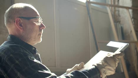 portret van senior timmermeester controleert de kwaliteit en de grootte van een houten plank in productie.