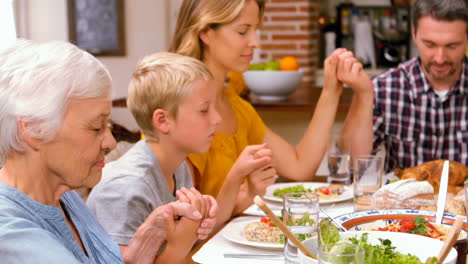 cute family praying before eating dinner