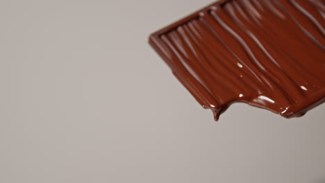 pull focus close up shot of melting chocolate bar against white background with copy space