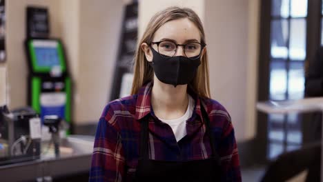 Portrait-of-a-woman-in-a-medical-mask-working-at-the-checkout-in-a-supermarket