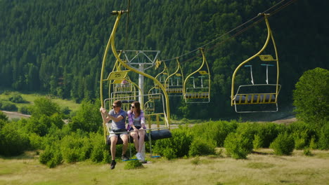 a happy young couple is riding on a ski lift photograph landscapes holidays in the mountains in summ