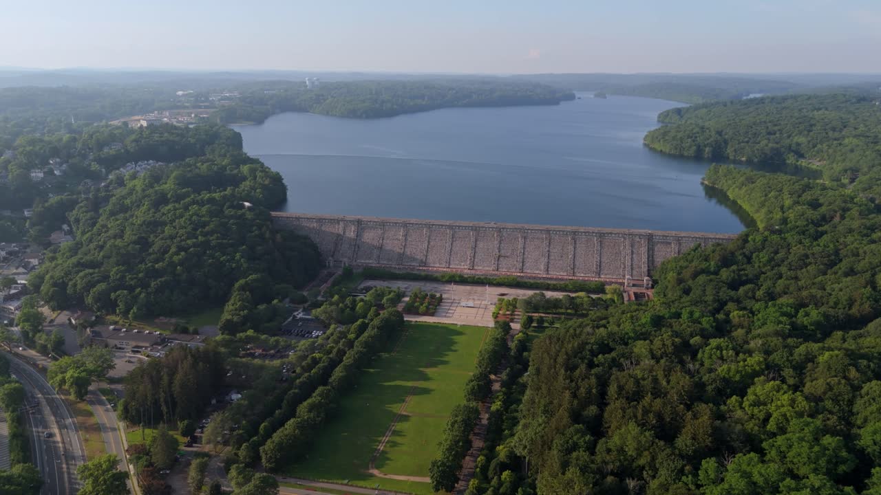 Traffic scene on interstate road near Kensico reservoir plaza dam in New York. Aerial wide shot. Cars on road in suburb of town