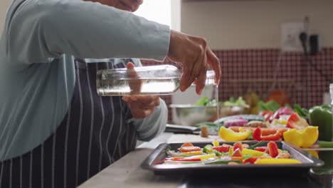 mujer asiática mayor vertiendo aceite de oliva sobre ensalada de verduras en la cocina en casa