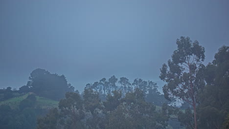 Toma-De-Timelapse-De-Niebla-Pasando-Sobre-Tierras-Altas-Cubiertas-De-Vegetación-Verde-A-Lo-Largo-Del-Campo-Rural-Durante-La-Mañana