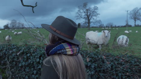 woman walking past field of sheep