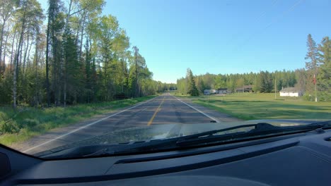 pov while driving on a narrow county road past past a few rural homes in forested area of northern minnesota in early spring