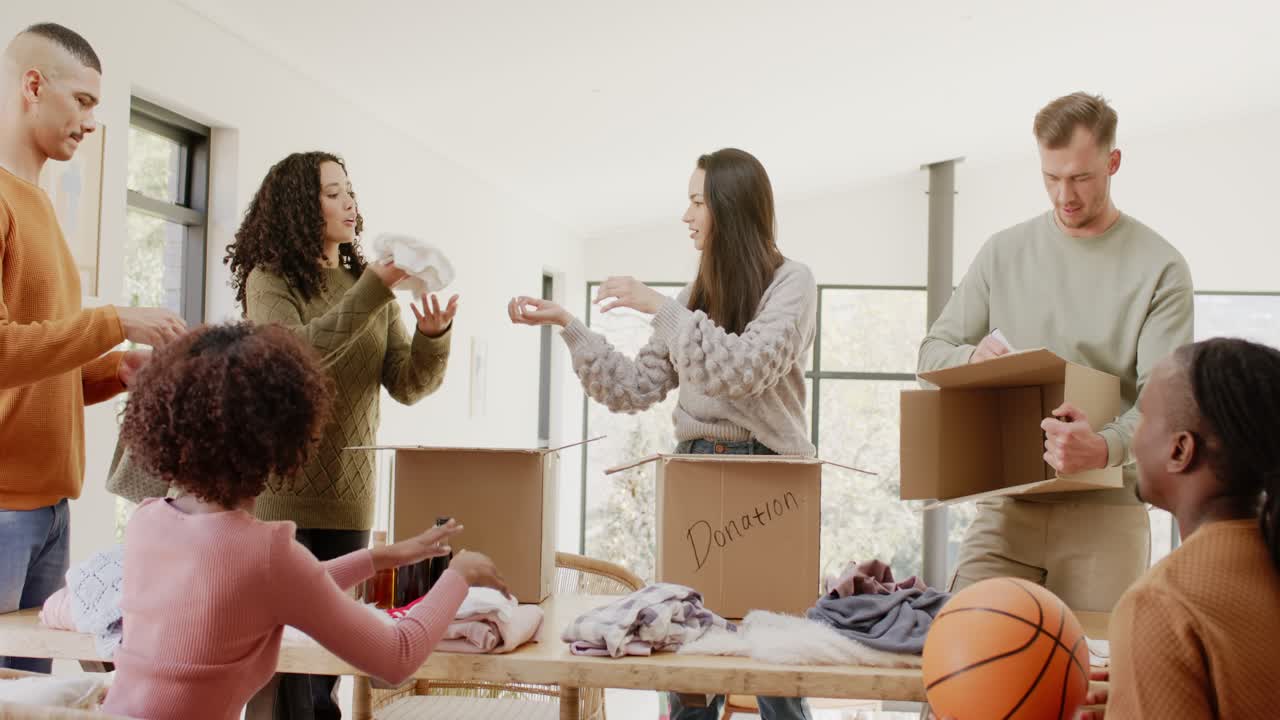 Diverse volunteers following woman instruction sorting clothing into donation boxes at wooden table