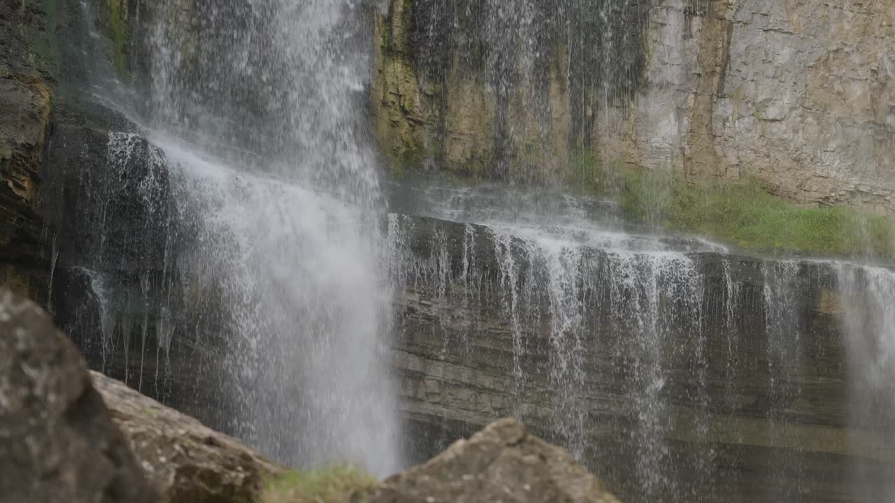 Water cascades down a rocky cliffside creating a peaceful natural waterfall scene