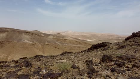 toma aérea, avanzada y rápida de drones moviéndose desde el suelo en la cima de una colina, revelando una hermosa vista del desierto y el cielo azul, en un día soleado