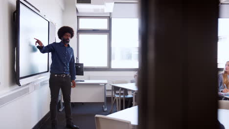 Male-High-School-Teacher-Standing-Next-To-Interactive-Whiteboard-And-Teaching-Lesson