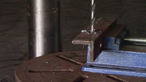 slow motion - drill press making steel shavings as it cuts through a section of steel angle iron