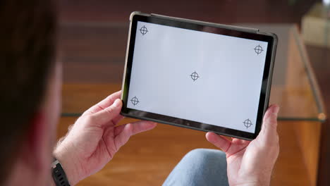 senior man holding tablet with blank screen at home, preparing for christmas, copy space