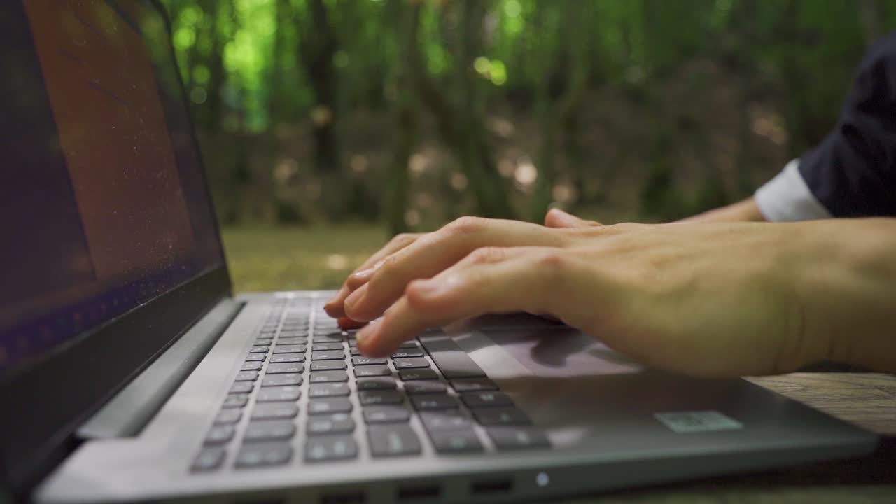 Close-up of hands typing on laptop keyboards in slow motion.