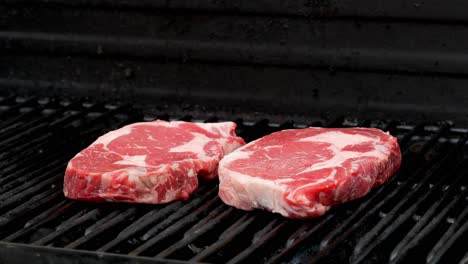 a raw rib eye steak is placed on a grill next to another one