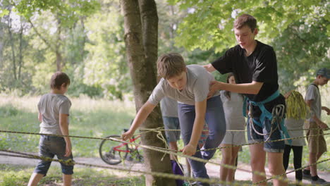 dziecko bez lęku wspina się na liny między drzewami. chłopiec w parku przygód przechodzi przeszkody na liniowej drodze.