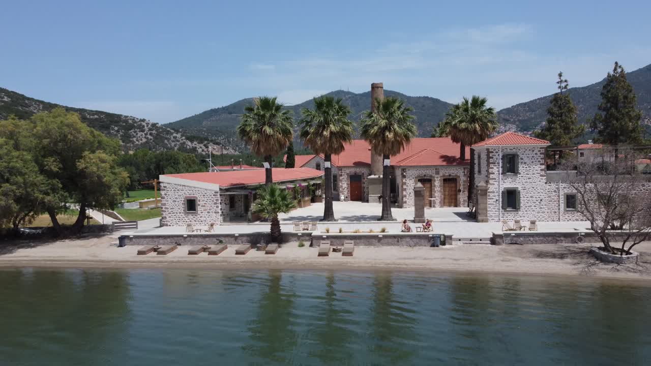 Tourist couple sunbathing in outdoor area of an isolated hotel property with private beach, Zaira hotel beautiful landscape surrounding hills and olive gardens, Lesvos Island, Drone shot
