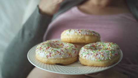 Video-Einer-Schwangeren-Frau,-Die-Im-Bett-Leckere-Donuts-Isst