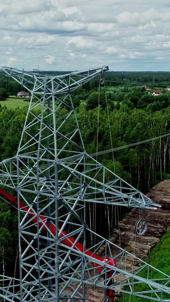 Drone pulls back from powerline tower installed in forest clearing for energy transfer, vertical