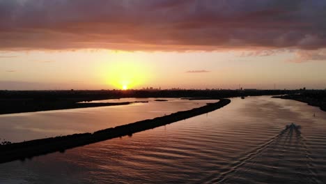 Sunset-on-a-Dutch-river-while-swallows-flying-around-and-speedboat-sailing-on-the-river