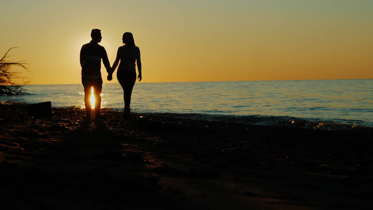 사랑에 빠진 커플의 실루, 해가 지면 해변이나 호수 에서 산책하는 모습, 태양의 아름다운 반임, 아시아인과 백인 여성